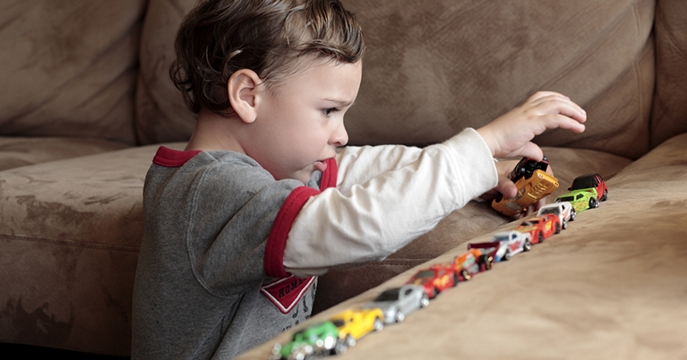 Autistic boy playing with toy cars