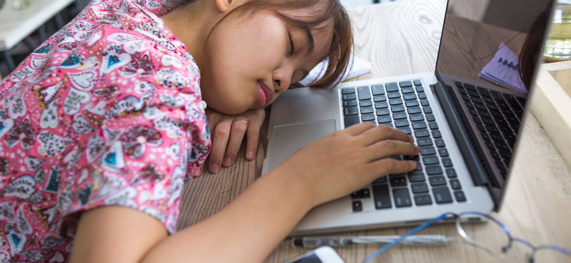 Asian girl resting on laptop with her hand on keyboard